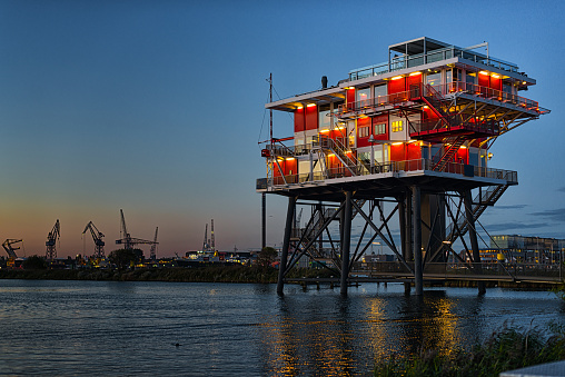 Amsterdam, Netherlands - September 22, 2017: REM island is a decommissioned oil platform in the heart of the port of Amsterdam. Nowadays the platform is used as office, bar, restaurant and observation deck. The photo was taken with along exposure at dusk in the blue hour. It’s worth to have a look if you have the chance to visit Amsterdam.Amsterdam, Switzerland - September 22, 2017: REM island is a decommissioned oil platform in the heart of the port of Amsterdam. Nowadays the platform is used as office, bar, restaurant and observation deck. The photo was taken with long exposure at dusk in the blue hour. It’s worth to have a look if you have the chance to visit Amsterdam.