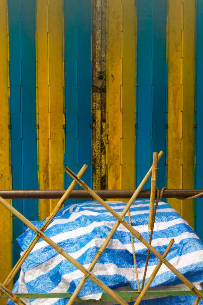 istock Abandoned rubbish beneath a striped tarpaulin, with bamboo screening. 937302036