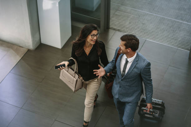 Business colleagues arriving at conference Top view of business colleagues arriving with luggage at conference. Business people with luggage walking together and chatting. business journey stock pictures, royalty-free photos & images