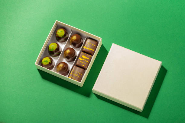 Assortment of luxury bonbons in box on green background stock photo