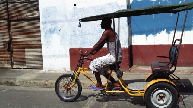 Bicycle taxi driver with his vehicle, Cuba