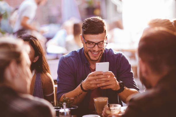 Happy hipster man at coffee shop texting on mobile phone