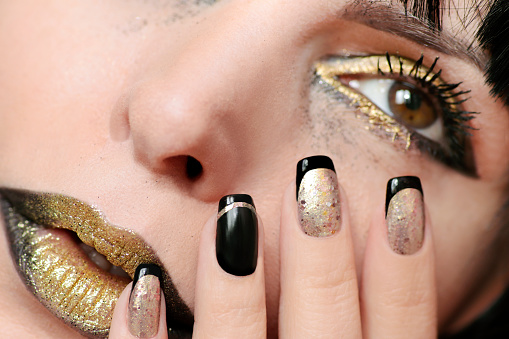 Fashionable black gold makeup and close-up nail design.