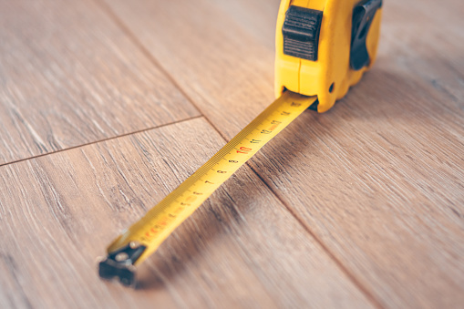 Medida de cinta de construcción en un suelo de madera photo