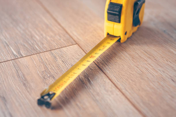 medida de fita de construção sobre um piso de madeira - tape measure centimeter ruler instrument of measurement - fotografias e filmes do acervo