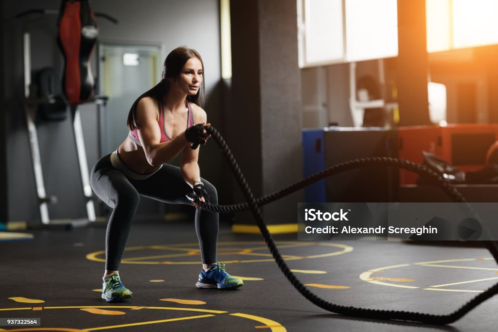 Athletic young woman doing gym exercises with a rope. Athletic young woman doing gym exercises with a rope Achievement Stock Photo