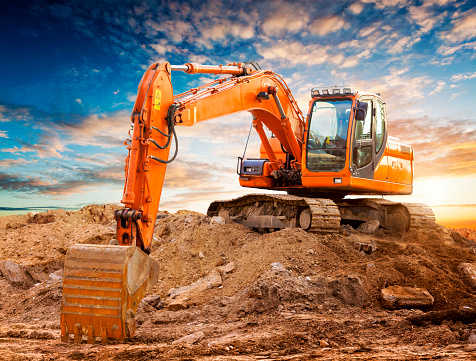 Excavator at a construction site against the setting sun. High quality image.