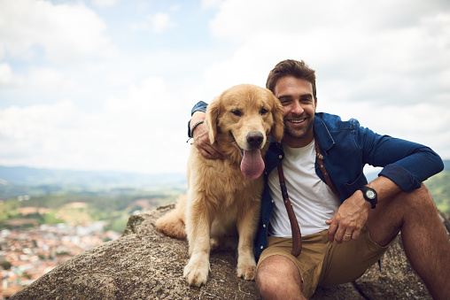 Cropped portrait of a handsome young man and his dog taking a break during a hike in the mountains