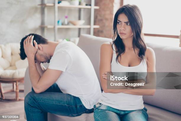 Mistrust And Cheat Problems Annoyed Couple Is Ignoring Each Other Sitting On The Couch Upset Indoors At Home I Am Not Talking To You Stock Photo - Download Image Now