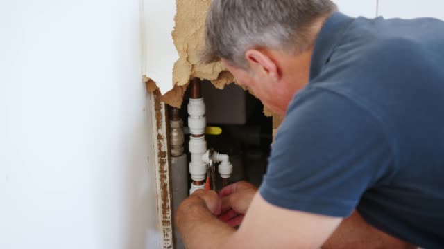 Close Up Of Domestic Plumber With Tools Repairing Leaking Pipe