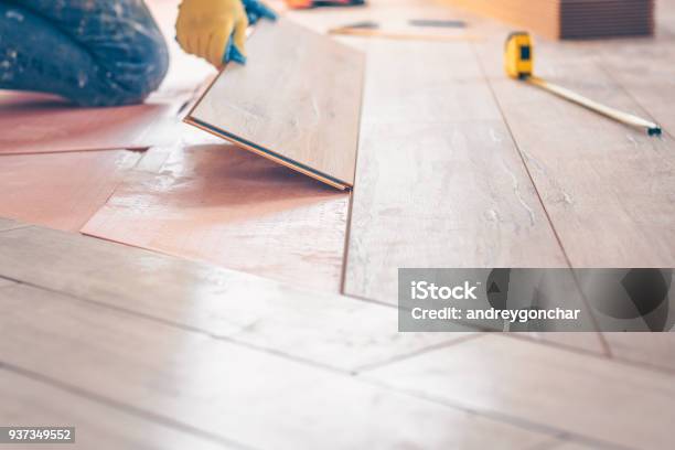 Professional Installation Of Floor Covering The Worker Quickly And Qualitatively Mounts A Laminate Board Stock Photo - Download Image Now