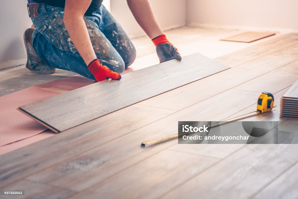 Worker professionally installs floor boards Flooring Stock Photo