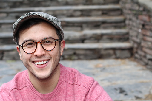 Hip man smiling wearing eyeglasses and hat.