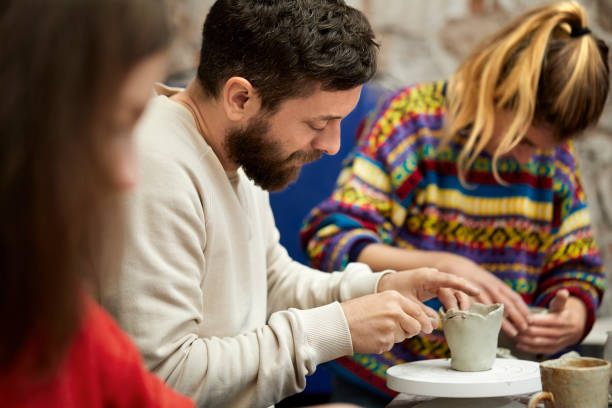 istock Mid adult man carving clay at table in workshop 937370402