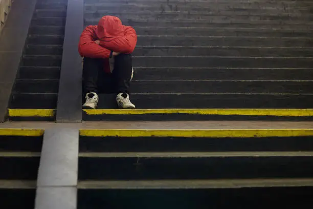 Photo of young homeless man sleeping on the street