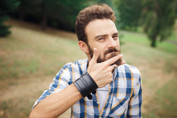 istock Young bearded hipster cut the beard with finger. Barbershop concept. 937375084