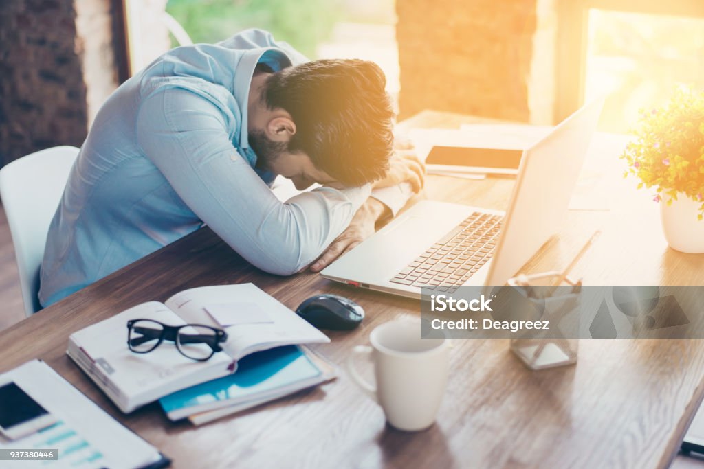 I need a vacation! Close up top view portrait of tired sick young brunet guy. He is wearing the formalwear, resting at the workplace Working Stock Photo