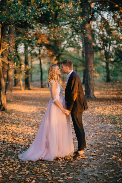 молодожены гуляют в лесу на закате - couple autumn embracing bridge стоковые фото и изображения