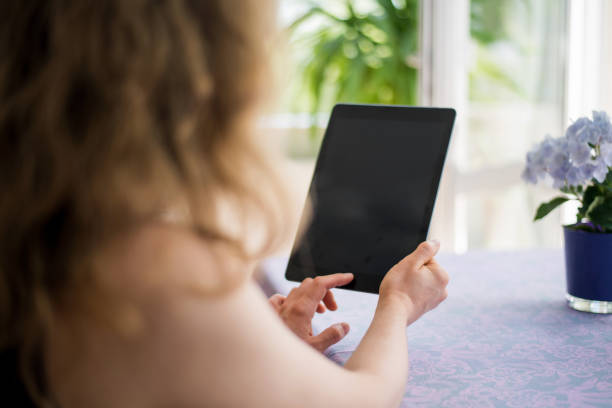 istock Blond woman is looking at a blank tablet computer screen with copy space 937399556