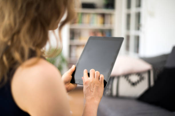 istock Blond woman is looking at a blank tablet computer screen with copy space on a summer day 937404200