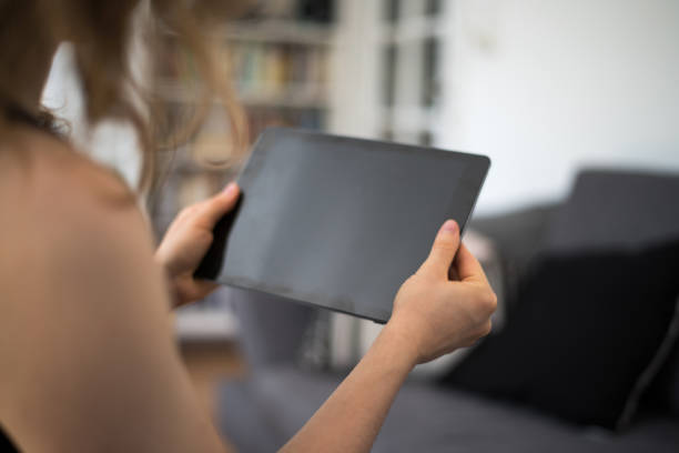 istock Blond young woman is looking at a blank tablet computer screen with copy space 937405834