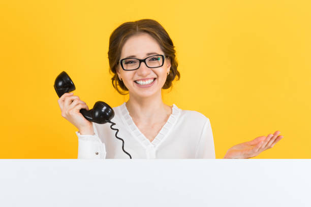 retrato de confianza hermosa excitada a sonriente mujer de negocios joven feliz con teléfono mostrando la cartelera en blanco sobre fondo amarillo - billboard businesswoman business confidence fotografías e imágenes de stock