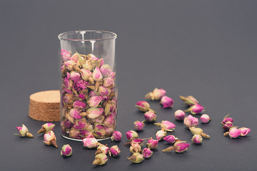 close close-up view of beautiful dry rose buds in glass jar on grey