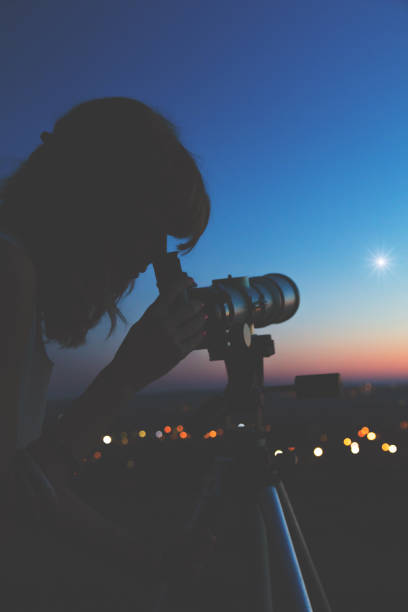 istock Young woman looking at the sky with astronomical telescope. 937407892