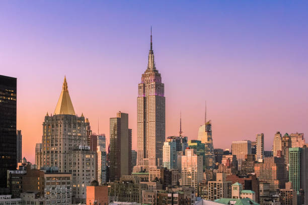 new york city skyline ao pôr do sol com o empire state building, arranha-céus de manhattan midtown e laranja-azul céu claro. - night empire state building building exterior horizontal - fotografias e filmes do acervo