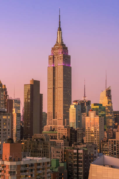 empire state building y el skyline de la ciudad de nueva york con rascacielos de midtown manhattan al atardecer con naranja cielo claro. - clear sky vacations vertical saturated color fotografías e imágenes de stock