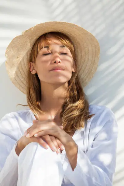 Photo of woman in the sun with closed eyes and a hat