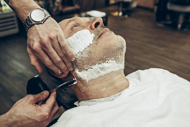 istock Close-up side top view handsome senior bearded caucasian man getting beard grooming in modern barbershop 937432500