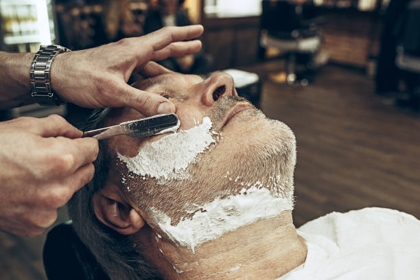 istock Close-up side top view handsome senior bearded caucasian man getting beard grooming in modern barbershop 937434800