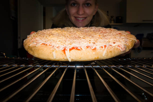 istock woman heating pizza in baking oven 937434828