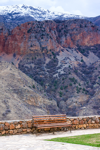 Lonely bench at territory of Medieval armenian Noravank monastery complex against red mountains, Armenia
