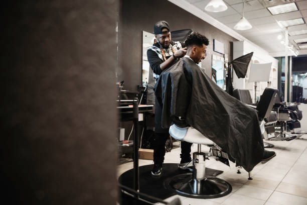 Barber Giving A Haircut in His Shop An African American man gets his hair cut by a skilled stylist at a small business barbershop. black barber stock pictures, royalty-free photos & images