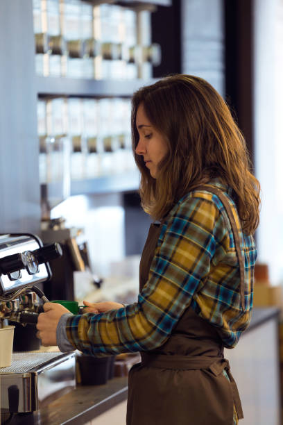 istock Beautiful young waitress making coffee using a professional machine in a coffee shop. 937444034