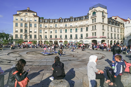 People and pigeons enjoy sunny day by  famous Osram sign at the Munich Karlsplatz (Stachus) on a busy day September 8 2017 Munich Germany