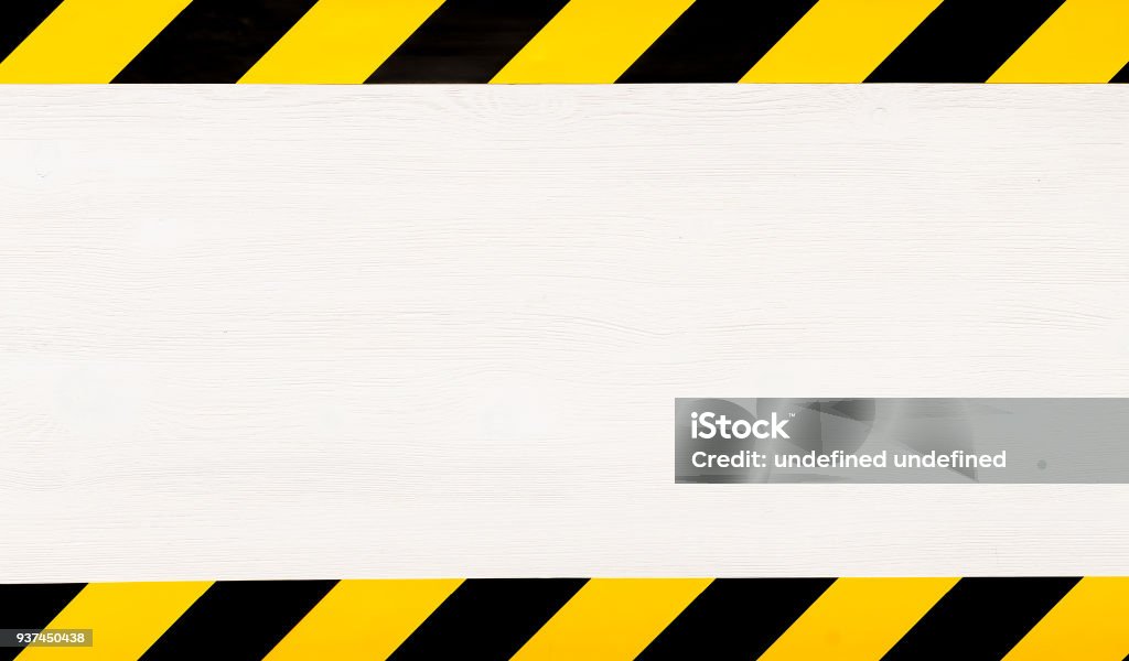 Under construction concept background. Warning tape. Under construction concept background. Warning tape frame on white wooden surface background with copy space. Barricade Tape Stock Photo