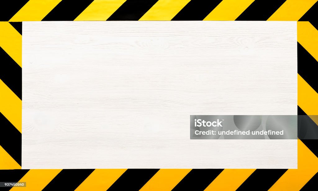 Under construction concept background. Warning tape. Under construction concept background. Warning tape frame on white wooden surface background with copy space. Safety Stock Photo