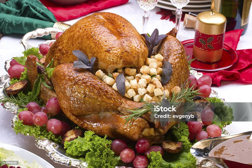 Large cooked Christmas turkey with all the trimmings Garnished roasted turkey on Christmas decorated table with candles and flutes of champagne Baked Stock Photo