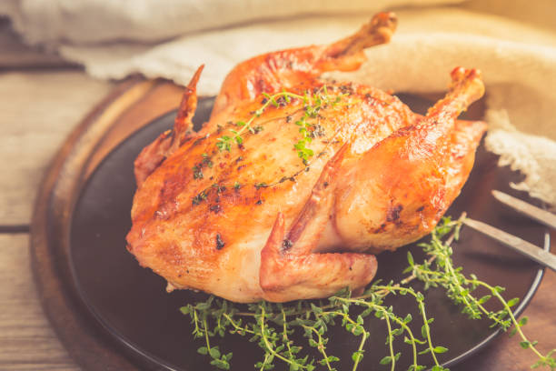 istock Fried whole chicken with herbs over natural wood background. whole roasted chicken 937451740