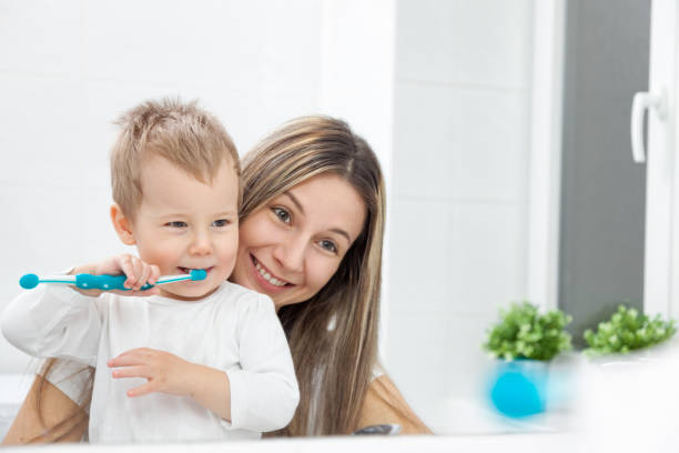 happy mother teaching her son how to bush teeth - human teeth child smiling family imagens e fotografias de stock