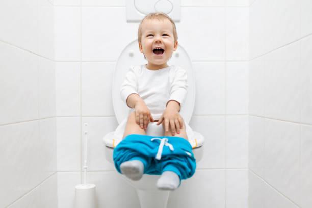 Adorable young child sitting on the toilet Adorable young child sitting and learning how to use the toilet potty training in babies stock pictures, royalty-free photos & images