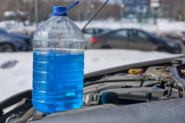 istock Canister with non-freezing liquid for windshield washer standing on the engine of a car in front of a road with cars in winter outdoors 937463068
