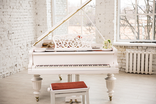 white grand piano standing in elegant white interior of Brick walls