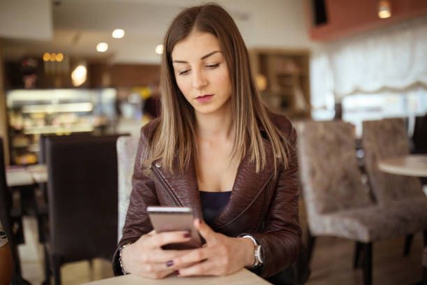istock Young woman using mobile phone in cafe 937466488