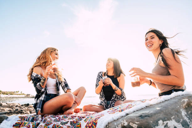 istock three young beauty women at the beach drinking a fruit juice 937478280