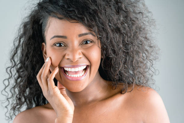 istock Stunning black young woman touching her face looking at camera laughing 937487348