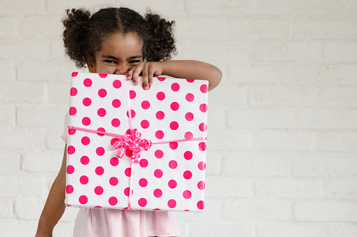 Mixed race sweet little girls holding gift for mother's day. She is four years old. The photo can be use also for father's day, valentine's day, birthdays. The photo was taken in Quebec Canada.